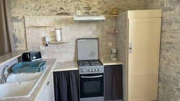 Une cuisine de taille réduite équipée d’une cuisinière à gaz, d’un four et d’un réfrigérateur.