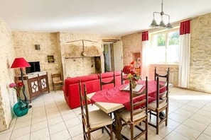 A room with a dining table, chairs, a red sofa, a TV, and a lamp. - ⭐ Nature Getaway with Pool & Jacuzzi - 6 People (MARTEL)