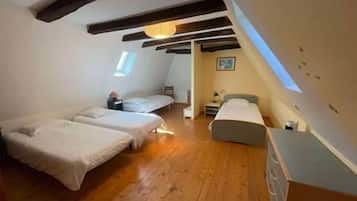 Een slaapkamer met twee bedden, houten vloeren en een schuin dak.