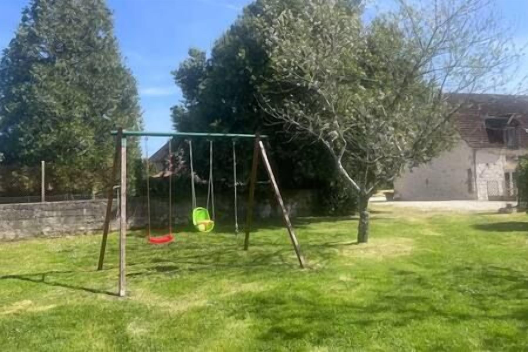 Een schommel in een gazon met een huis op de achtergrond.