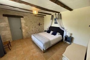 A bedroom with a bed, a nightstand, a chair, and a stone wall. - ⭐ Large family home for 15 people - Swimming Pool & Jacuzzi (MARTEL)