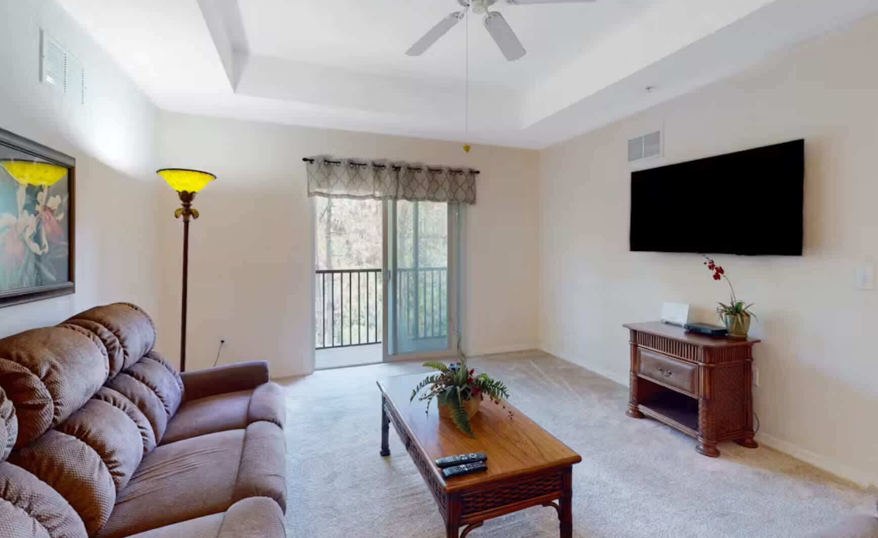 Un salón con sofá, una mesa de centro, televisión y balcón con vistas.