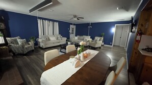 Un soggiorno con un tavolo da pranzo, due divani e una ventola a soffitto.