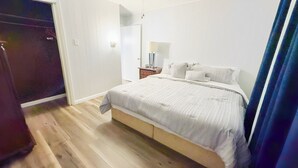 Una camera da letto con un letto, un comodino, una lampada e una porta.