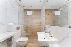 Ein modernes Badezimmer mit Waschtisch aus Marmor, einer weißen Toilette und einer Duschkabine.