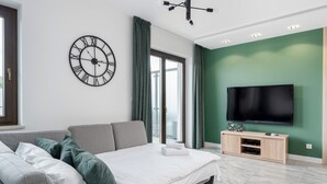 A modern bedroom with a bed, a TV, and a large wall clock.