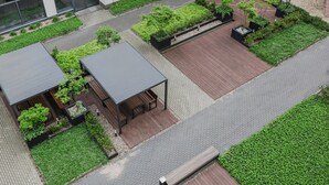 An aerial view of a modern building with a landscaped courtyard, including a wooden deck, seating areas, and various plants. - Warta River Cozy Vibe Studio (Poznań)
