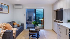 A modern living room with a sofa, a small table, and a TV.