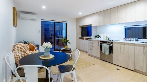 A modern kitchen with wooden cabinets, a built-in oven, and a large window.