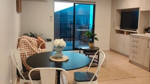 A modern living space with a dining area, a kitchen, and a large sliding glass door leading to a balcony.