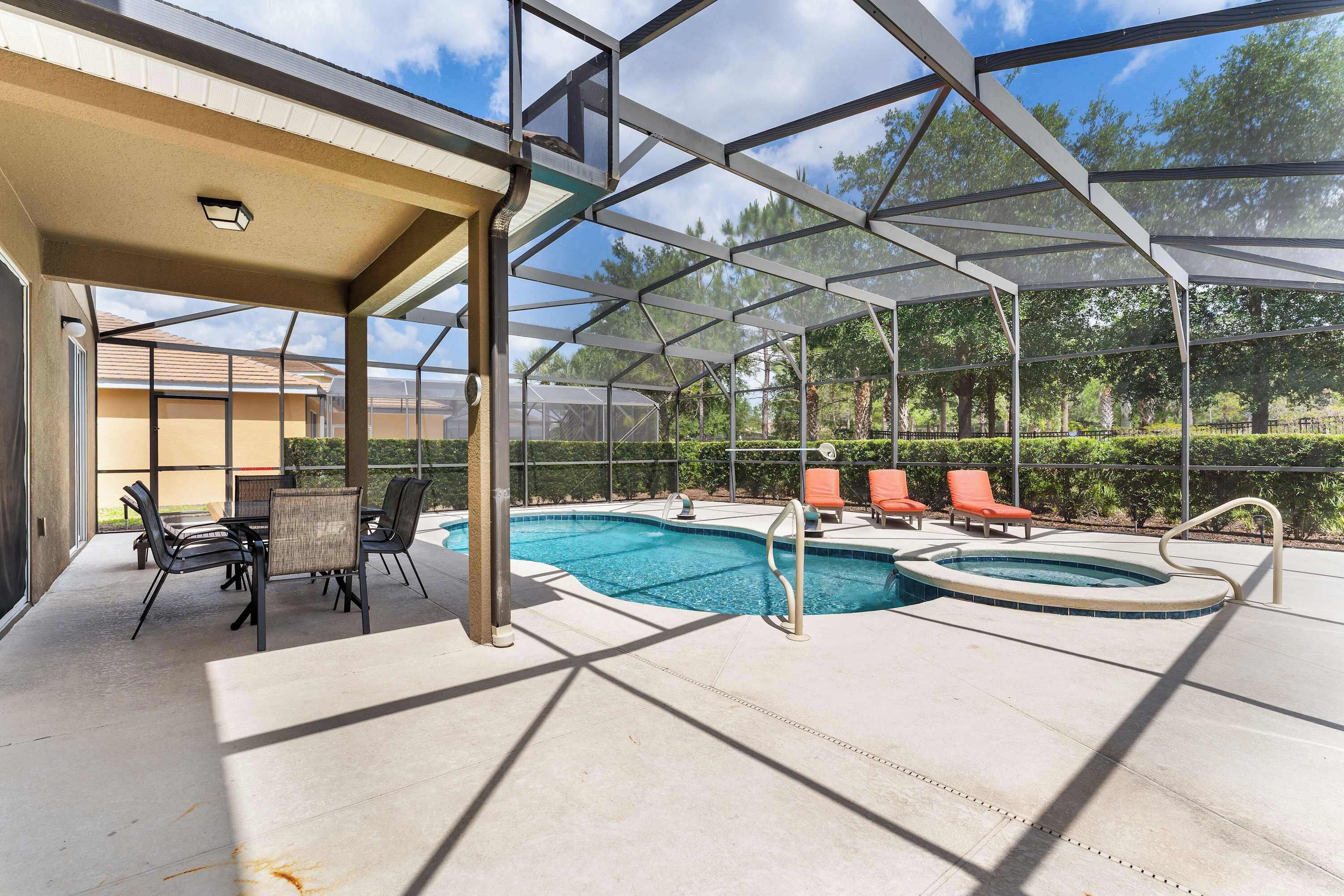 Un área de piscina techada al aire libre con un jacuzzi, sillas de descanso y una mesa con sillas.