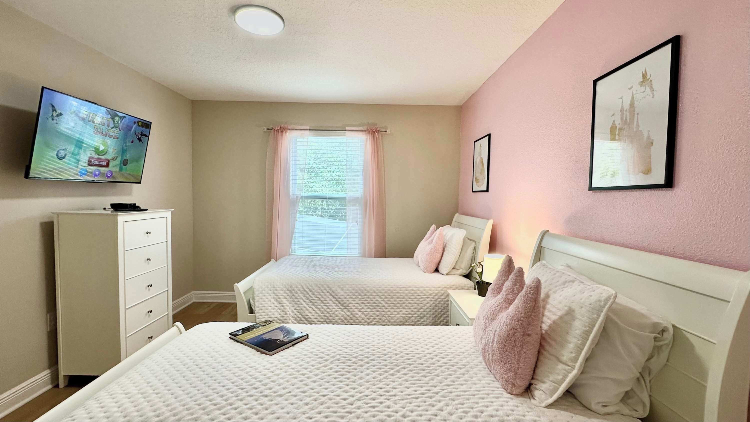 A bedroom with two beds, a TV, a dresser, and a window with curtains.