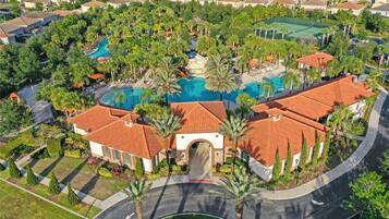 A resort with a central swimming pool, palm trees, and a red-tiled building.