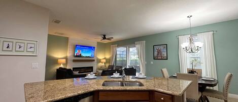 A modern kitchen with granite countertops, a built-in dishwasher, and a dining area with a chandelier.