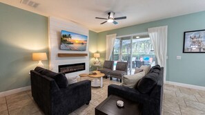 A living room with a fireplace, two sofas, a coffee table, and a TV mounted on the wall.
