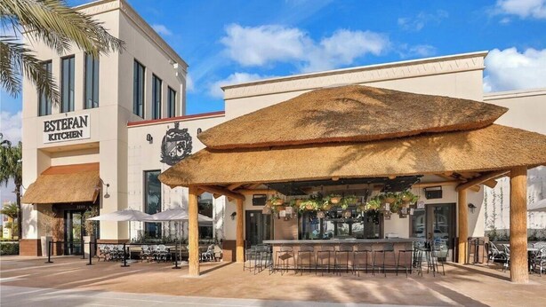 A restaurant with outdoor seating, a thatched roof, and a sign reading "ESTEFAN KITCHEN". - Tropical Vibes (Kissimmee)