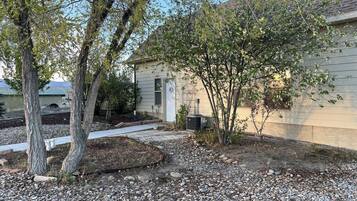 A residential property with a gravel driveway, a small garden area, and a house with a green roof.