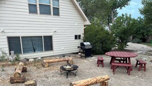 A backyard with a wooden deck, a barbecue grill, and a picnic table with benches. - Charming farmhouse in Price (Price)