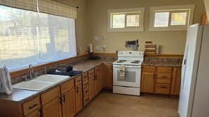 A kitchen with a stove, sink, and refrigerator. There are windows above the sink and stove. - Charming farmhouse in Price (Price)