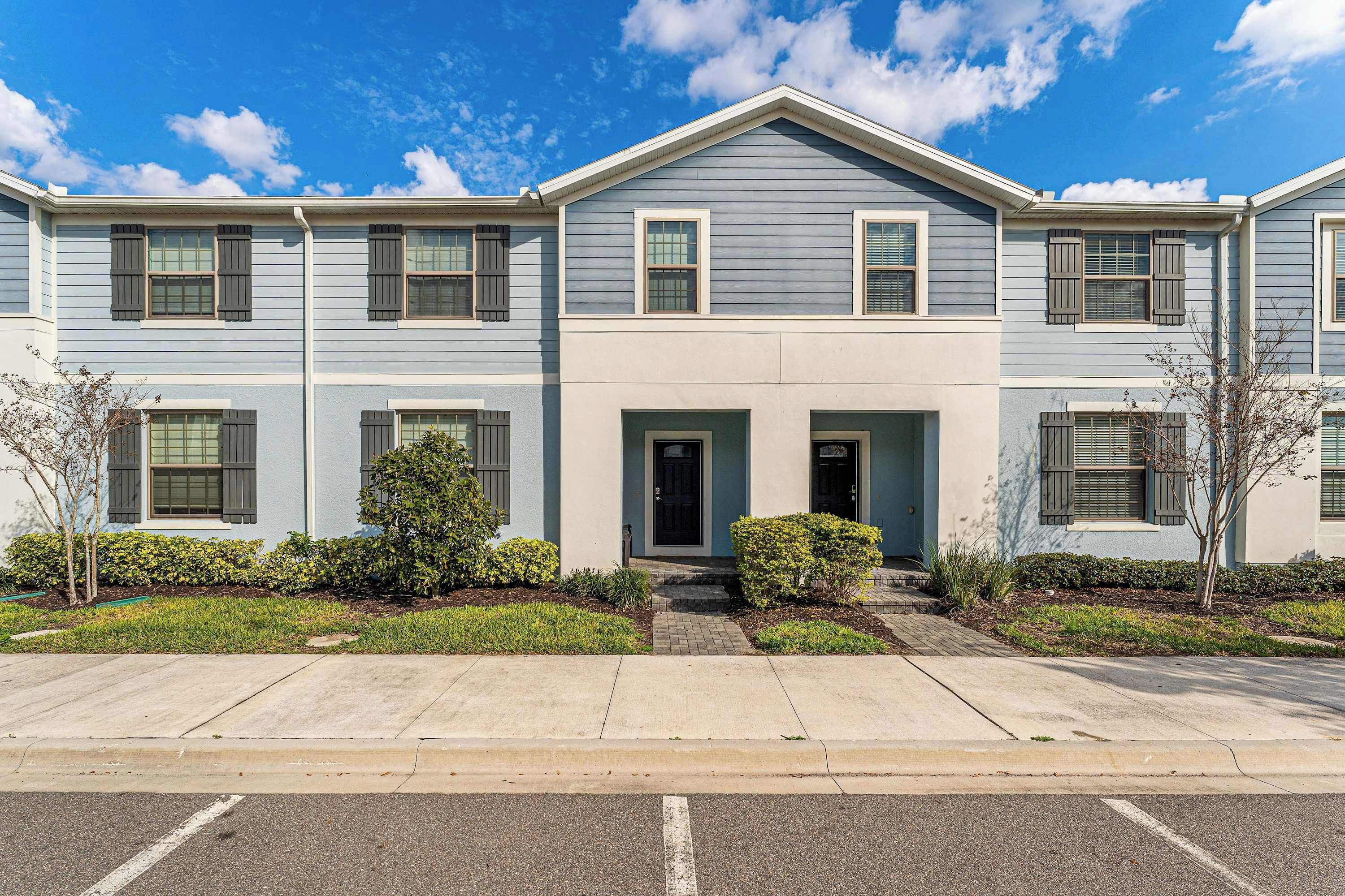 A two-story residential building with a central entrance, a small porch, and a driveway.