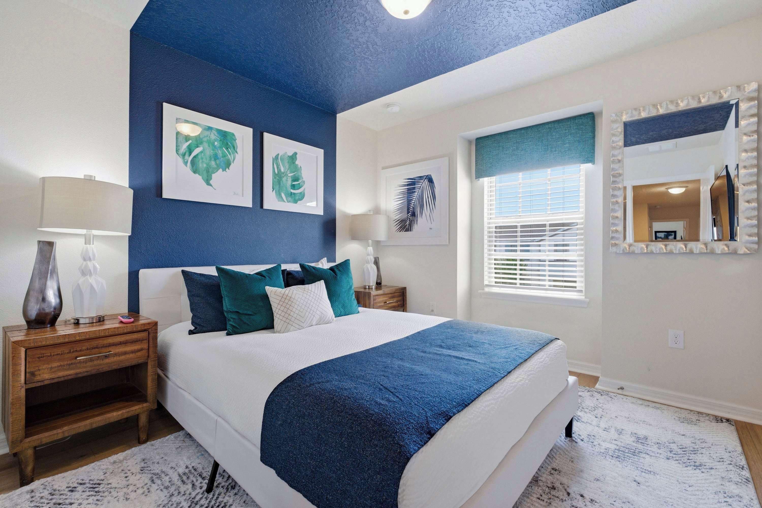 A bedroom with a large bed, two nightstands, a mirror, and artwork on the walls.