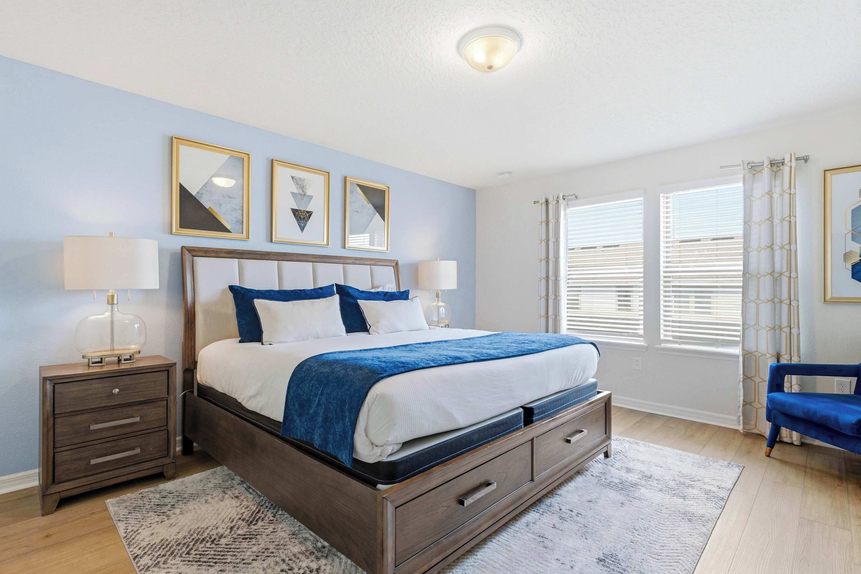 A bedroom with a bed, nightstands, a dresser, a chair, and a window with blinds.
