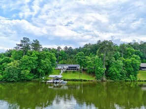 A lakeside property with a dock, a boat, and a house surrounded by dense trees.