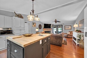 A spacious kitchen with a large island, dark cabinetry, and a ceiling fan.
