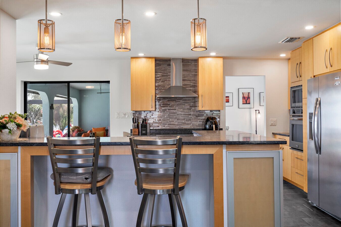 A modern kitchen with a central island, stainless steel appliances, and pendant lighting.