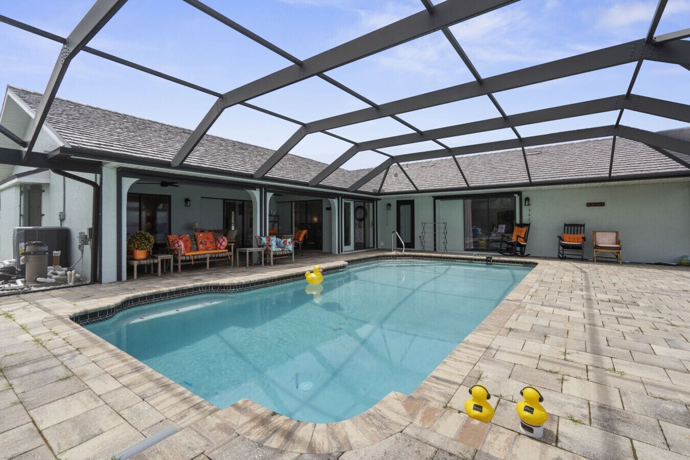Une piscine intérieure dotée d’un toit en verre, entourée de chaises longues et d’un patio couvert.