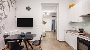 Une cuisine moderne avec des meubles blancs, une cuisinière noire et un coin repas comprenant une table et des chaises noires.