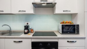 Une cuisine moderne équipée d’un évier en acier inoxydable, d’une machine à café, d’un four à micro-ondes et d’un four encastré.