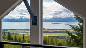 Una habitación con un amplio ventanal que ofrece vistas a un lago, montañas y un paisaje boscoso.
