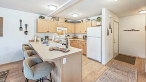 Une cuisine moderne avec des meubles en bois, un îlot central doté de tabourets de bar et un réfrigérateur.