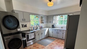A compact kitchen with a built-in washer and dryer, a sink, a stove, and a refrigerator. - Charming 3-bedroom 2-bathroom house with ATV access (Calumet)