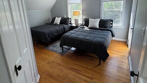 A bedroom with two beds, a window, a door, and a ceiling light. - Charming 3-bedroom 2-bathroom house with ATV access (Calumet)