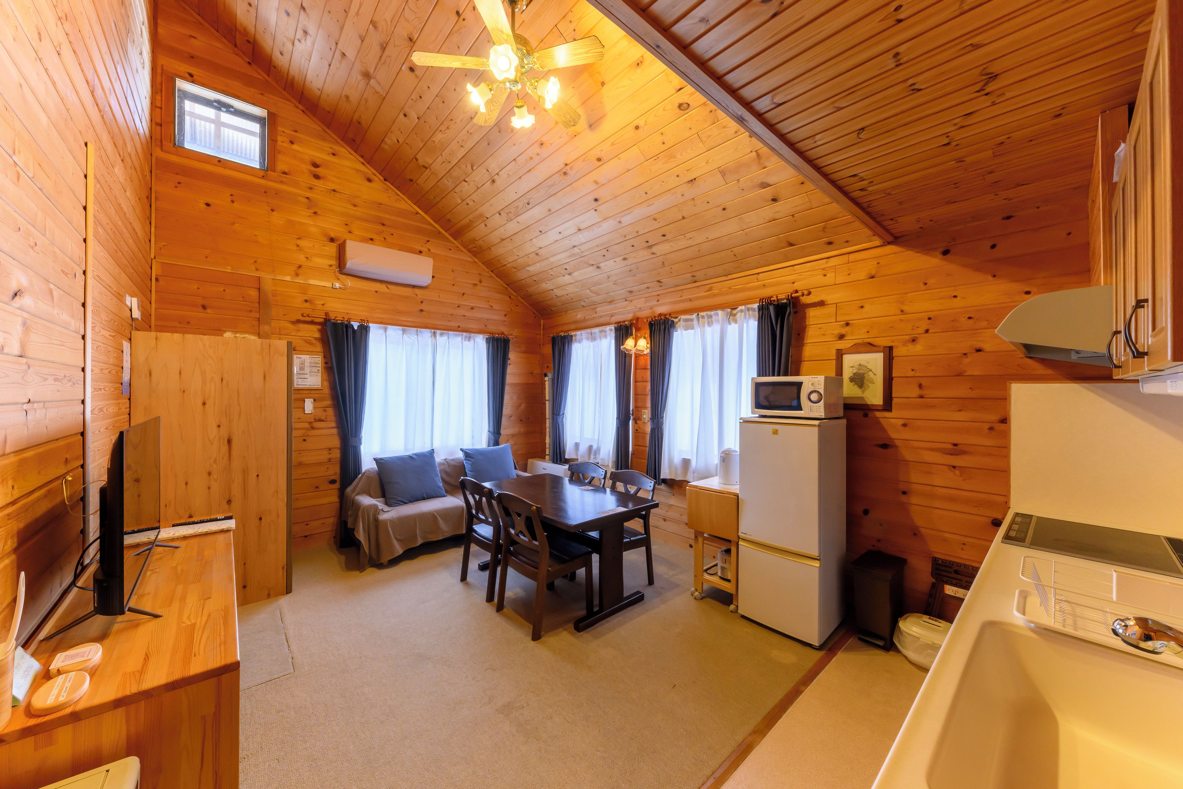 Interior acolhedor de uma cabana com área de jantar, cozinha e ventilador de teto.