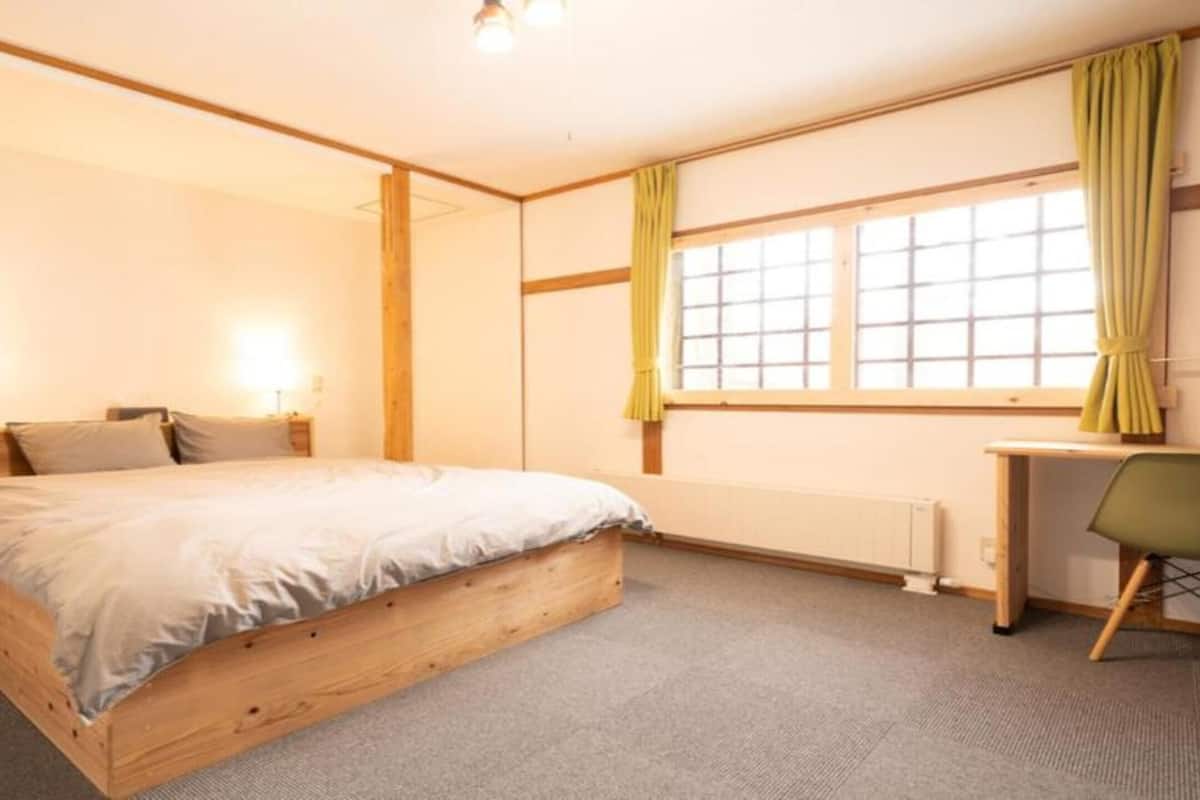 A bedroom with a wooden bed, a desk, and a chair.