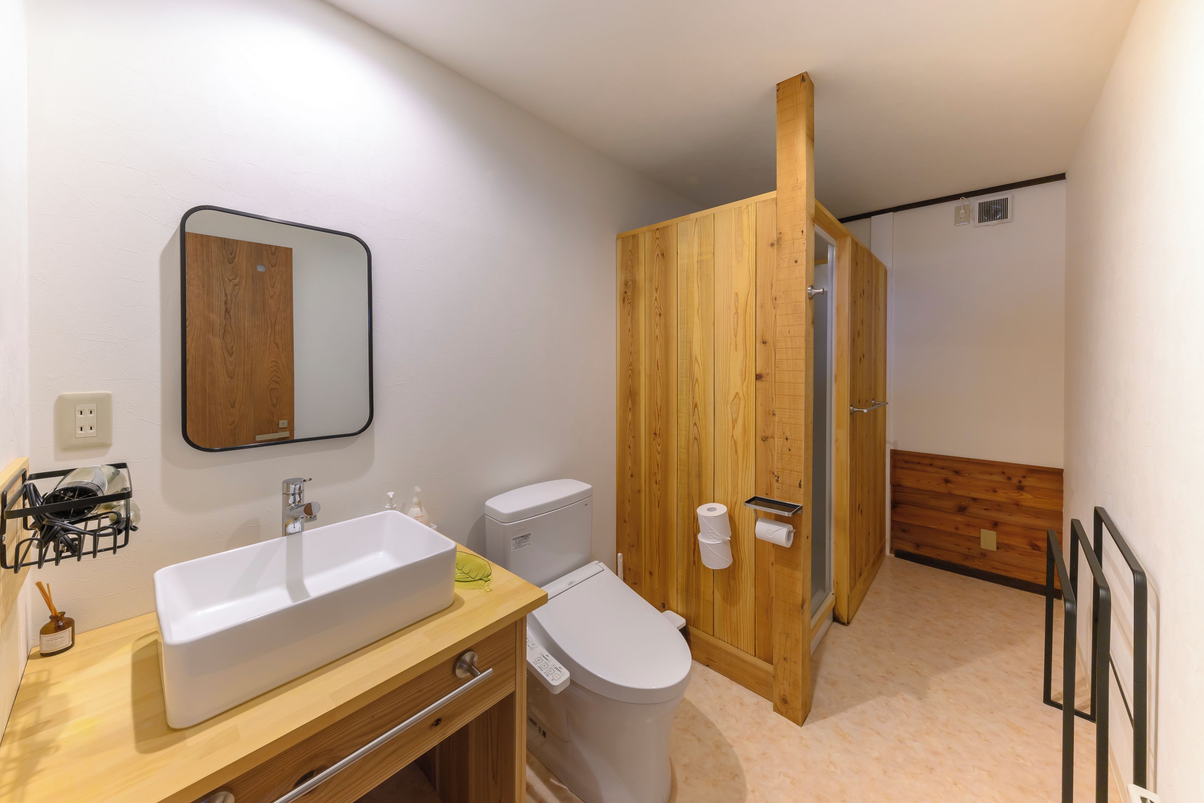 Un baño con tocador de madera, un lavabo blanco, un inodoro y una puerta de madera.