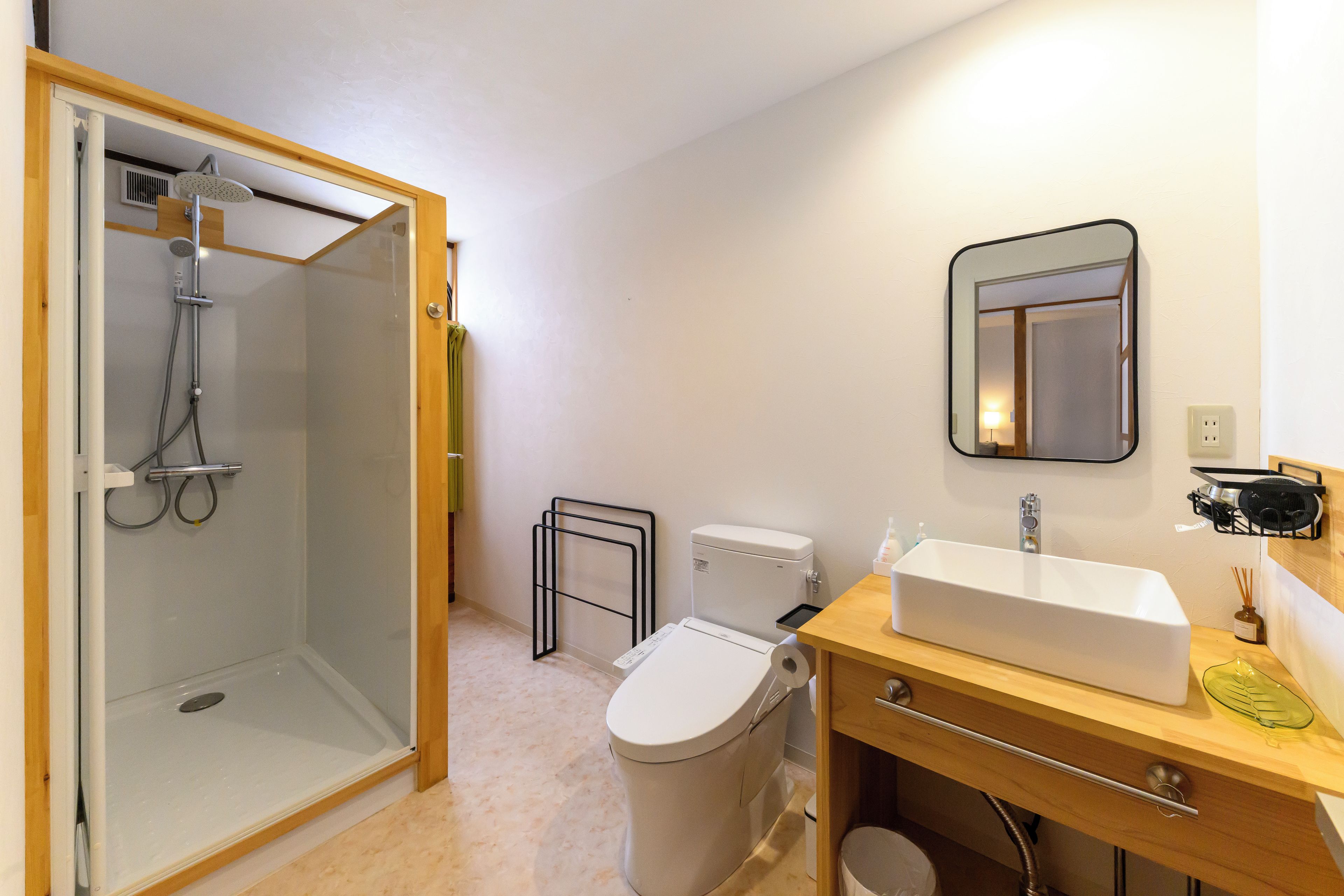 Een badkamer met een douche, toilet, wastafel en spiegel.