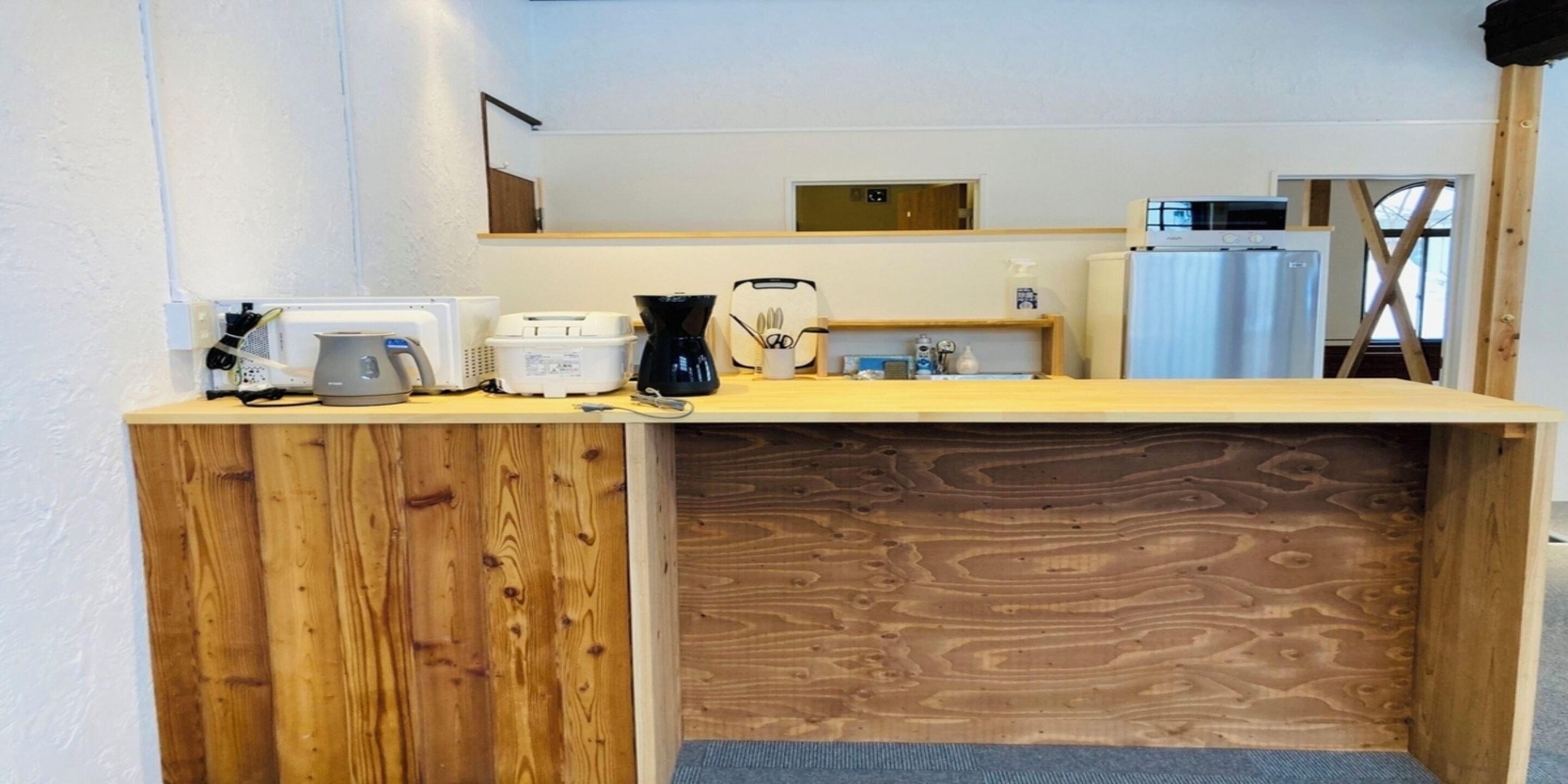 Eine Holztresen mit Kaffeemaschine, einer Mikrowelle und einem kleinen Regal mit Gegenständen.
