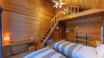 A wooden cabin room with two beds, a ceiling fan, a staircase, and a heater.