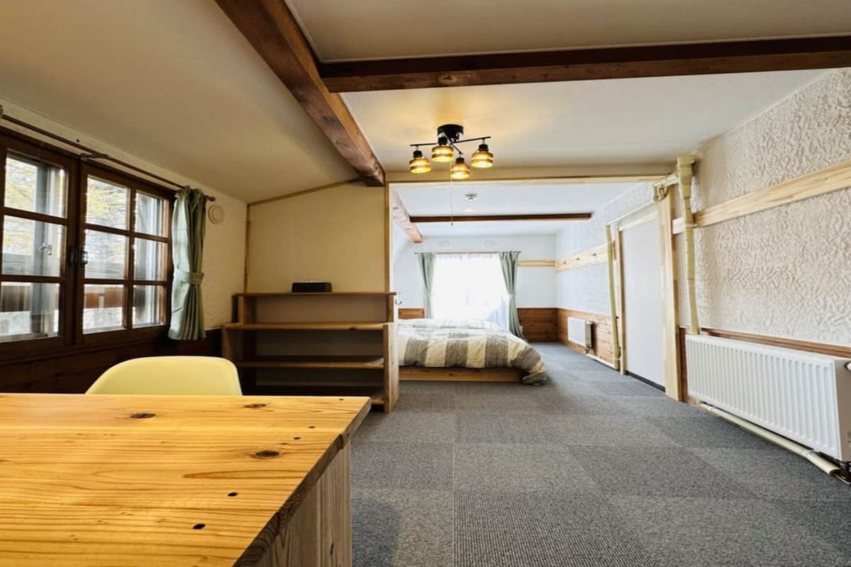 A room with a wooden table, chairs, a bed, and a radiator.