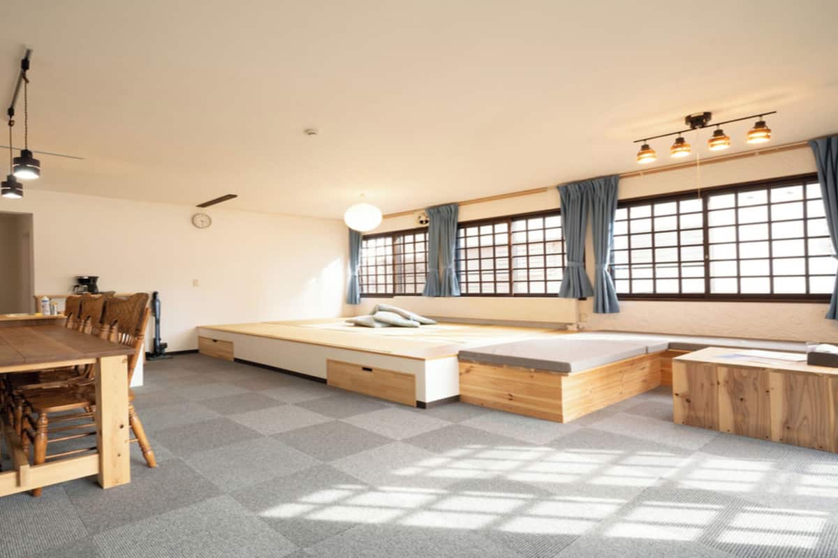 A compact living space with a dining table, chairs, a sofa bed, and a small kitchen area.