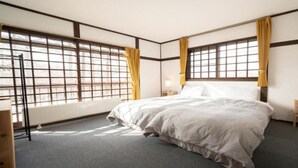 A hotel room with a large bed, two bedside tables, a nightstand, and a window with a view. - Madarao Vacances Village (Myoko)