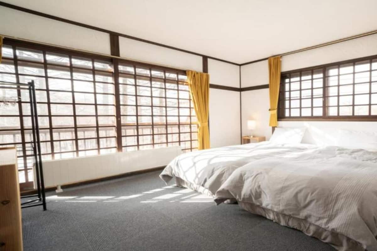 A hotel room with a large bed, two bedside tables, a nightstand, and a window with a view.