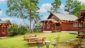 A rustic cabin-style building with a porch and string lights. - Madarao Vacances Village (Myoko)