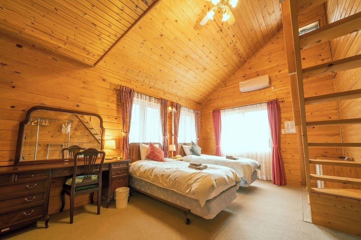 A wooden cabin bedroom with a bed, a desk, and a chair.