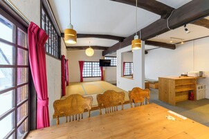 A traditional tatami mat room with wooden furniture and a large window with red curtains.
