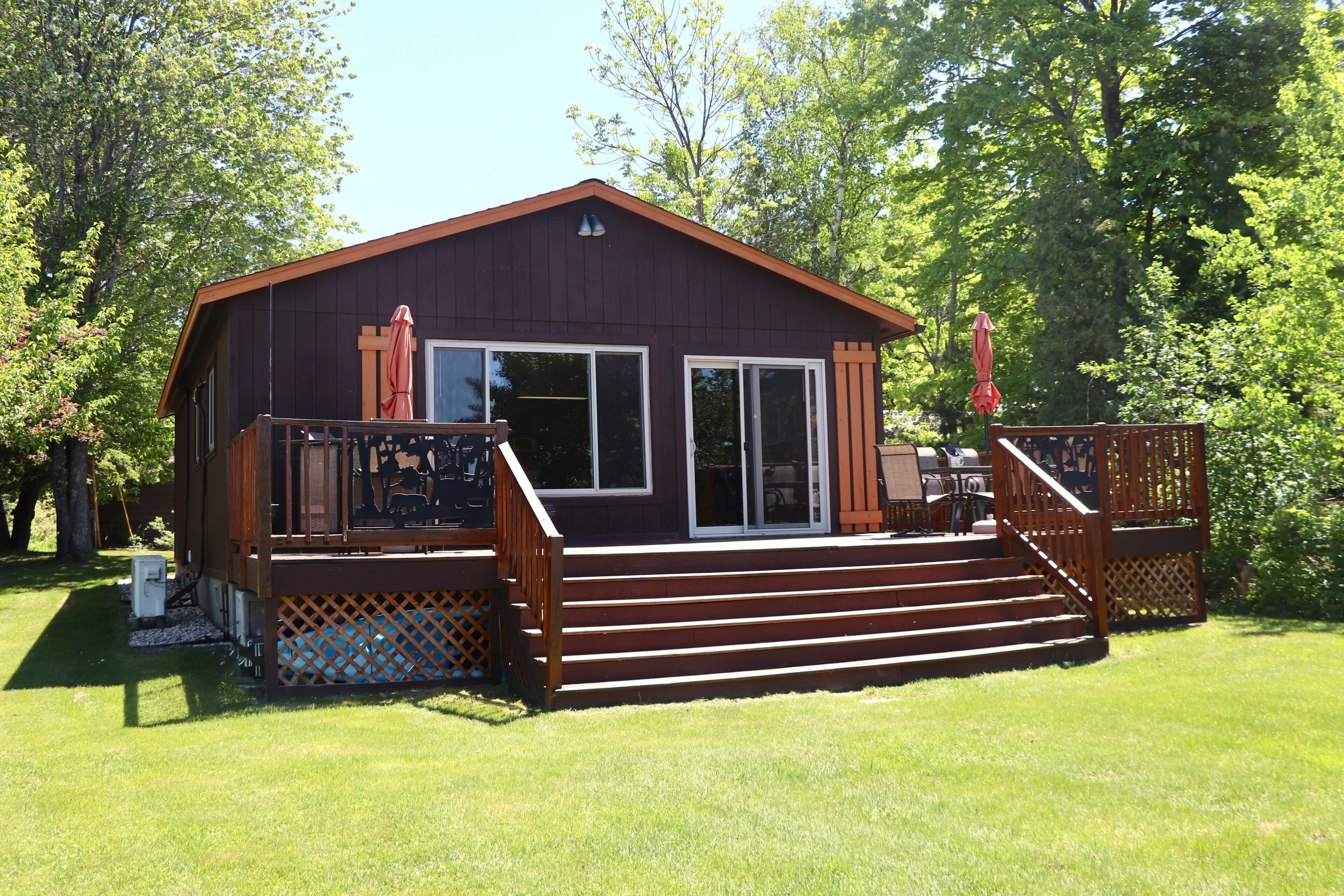 A cabin with a deck, a covered patio, and a large window.